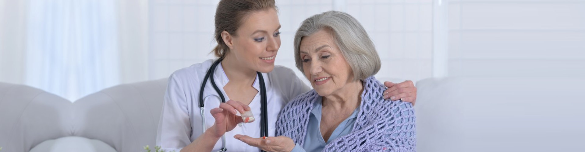 caregiver giving elder woman a medicine